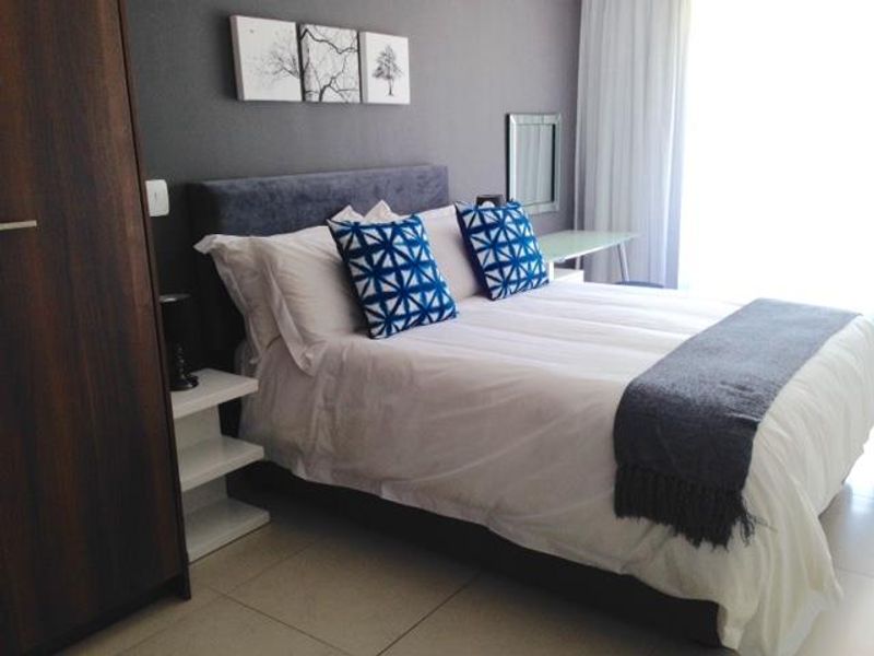 A well-maintained bedroom featuring neutral tiled flooring and a built-in wardrobe, offering a clean and functional living space.