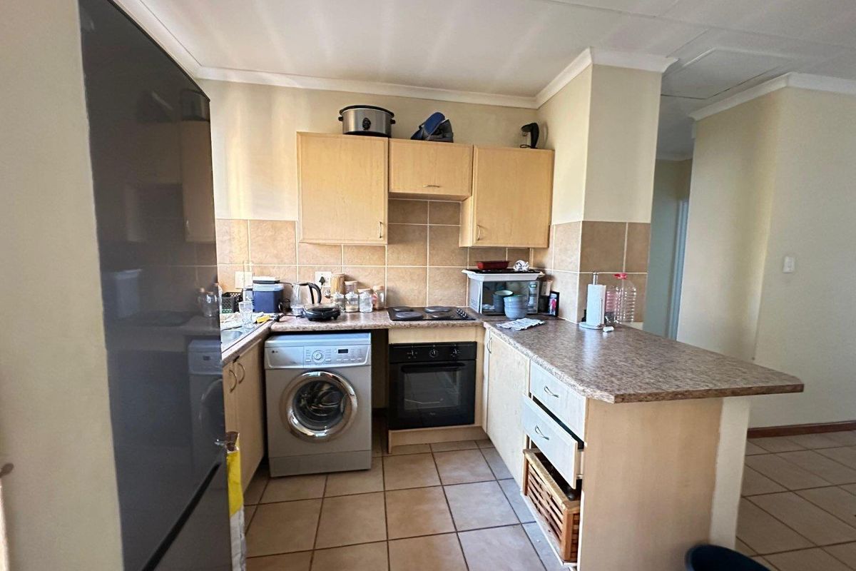A functional kitchen featuring built-in cabinetry, laminate countertops, a tiled backsplash, and integrated oven and hob, with a convenient breakfast bar layout.