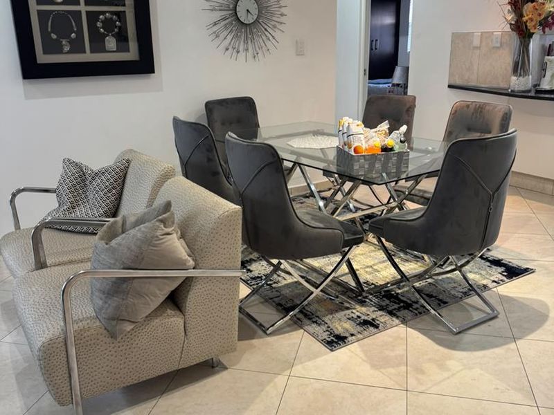 Open-plan living and dining area featuring tiled flooring, recessed downlighting, and a breakfast bar connecting to the kitchen space.