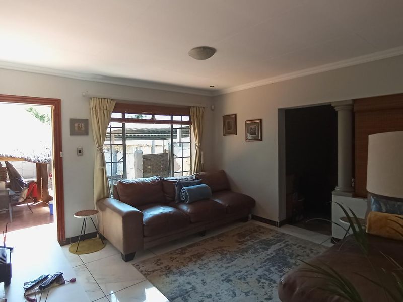 A living room featuring tiled flooring, a coved ceiling, and direct access to an outdoor patio area through a sliding door.