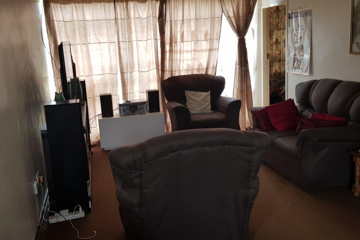 A living room area featuring carpeted flooring and a large sliding glass door providing natural light.