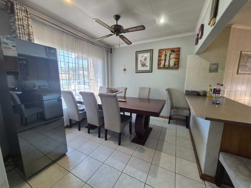 Open plan dining area featuring tiled flooring, a breakfast bar, and a ceiling fan, creating a functional space for meals and entertaining.