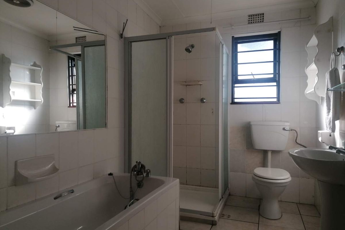 A dated bathroom featuring a separate shower enclosure, bathtub, pedestal basin, and toilet, with tiled finishes throughout.