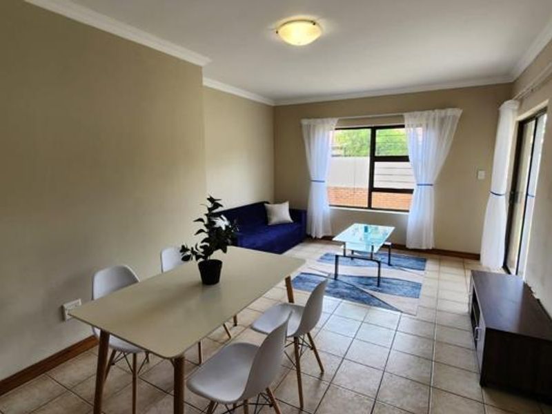 An open-plan living and dining area featuring tiled flooring, coved cornicing, and a sliding glass door providing access to the exterior.
