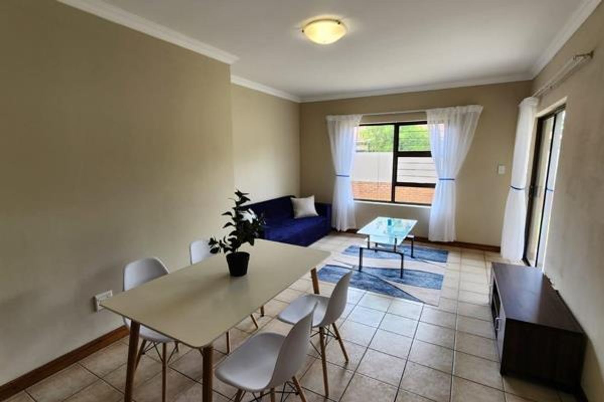An open-plan living and dining area featuring tiled flooring, coved cornicing, and a sliding glass door providing access to the exterior.
