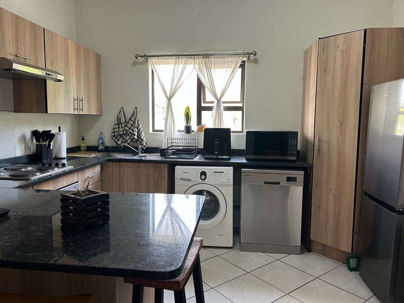 Functional kitchen featuring wood-look cabinetry, granite countertops, integrated appliances, and tiled flooring, offering a practical and well-organized cooking space.