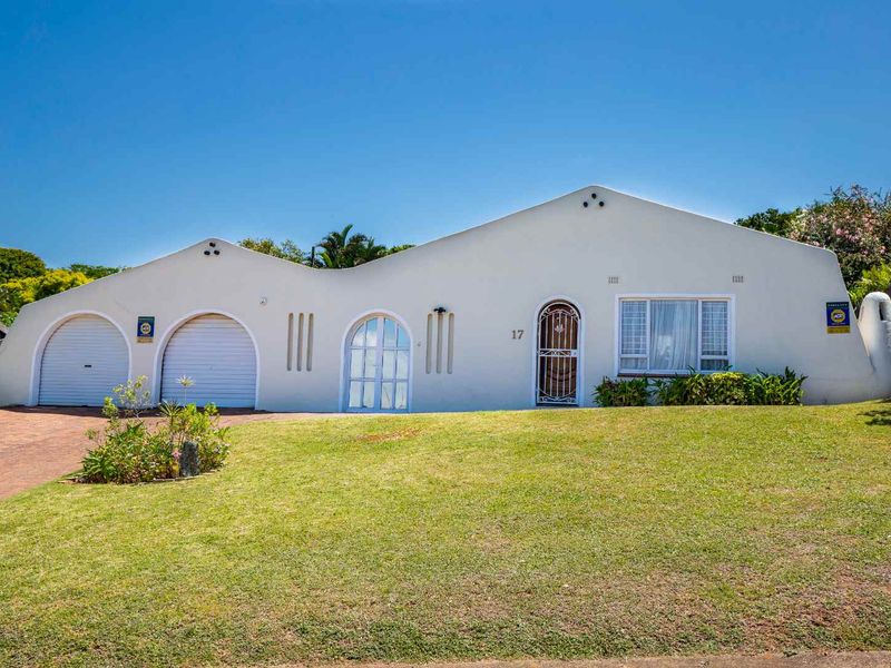 Front elevation of a single-story house featuring a double garage, arched entrance, and a well-maintained front lawn.