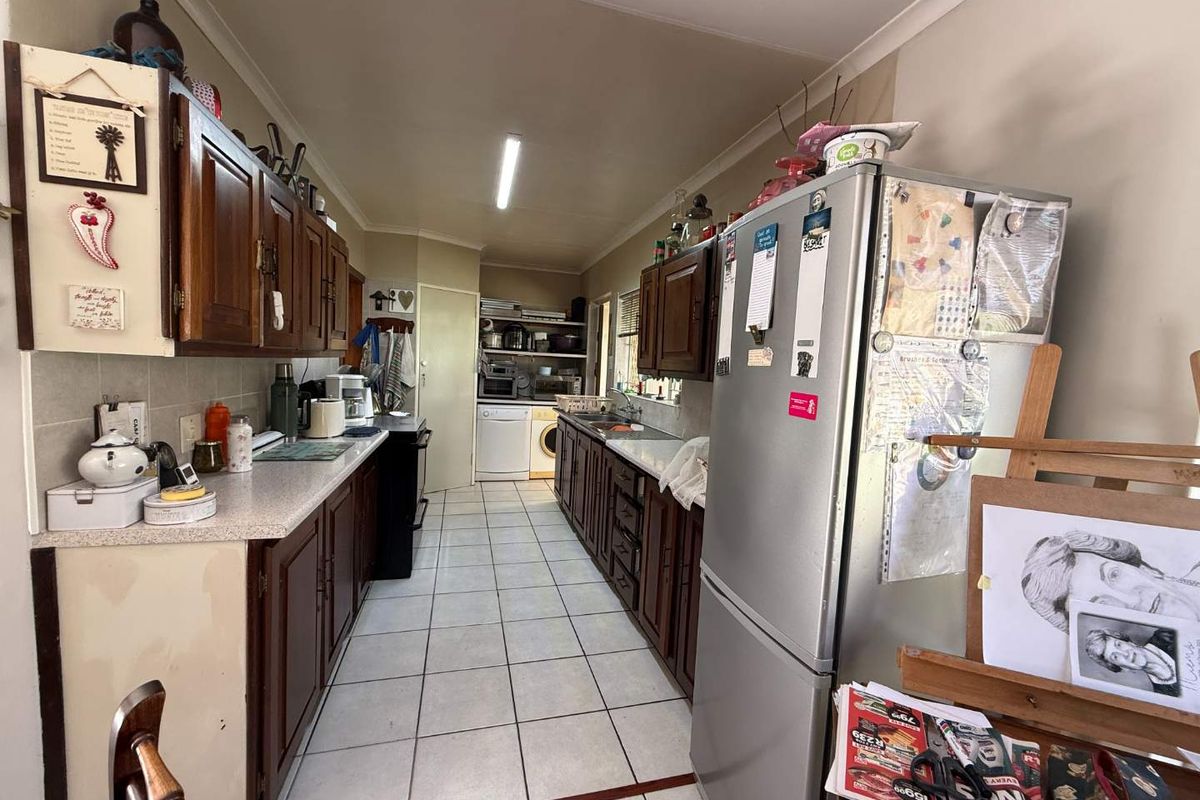 Galley-style kitchen featuring timber cabinetry, laminate countertops, and ceramic floor tiles, offering a functional layout with integrated laundry space at the rear.