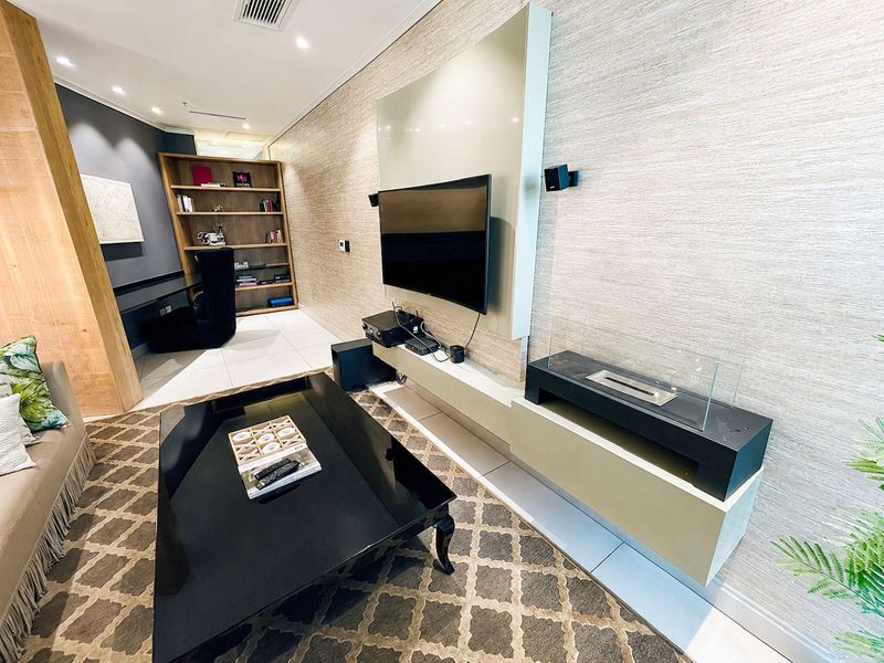 Modern living room featuring a sleek built-in media console, integrated bioethanol fireplace, recessed lighting, and custom shelving in a contemporary penthouse setting.