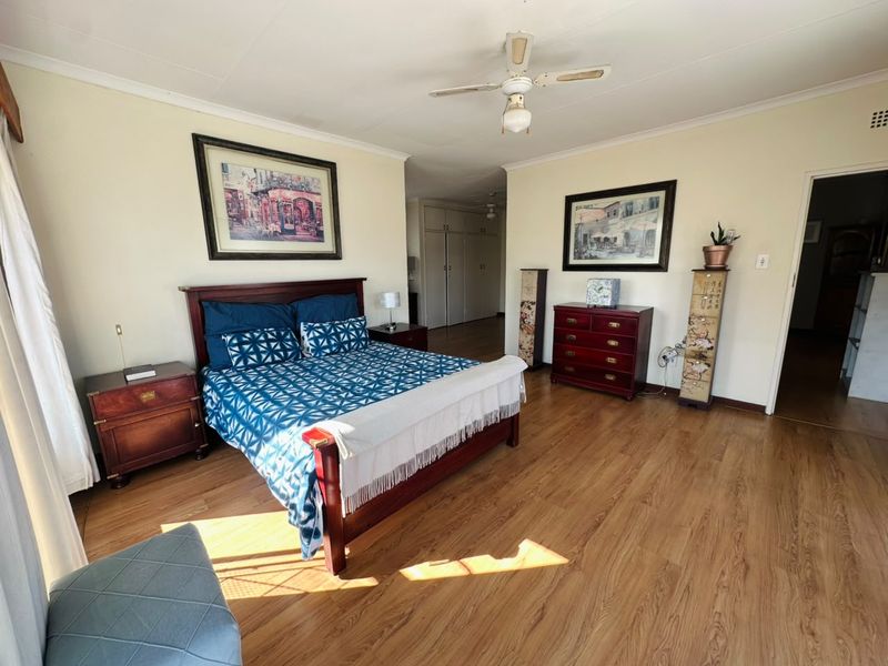 Spacious bedroom featuring laminate flooring, a ceiling fan, and built-in cupboards, offering a comfortable and functional living space.