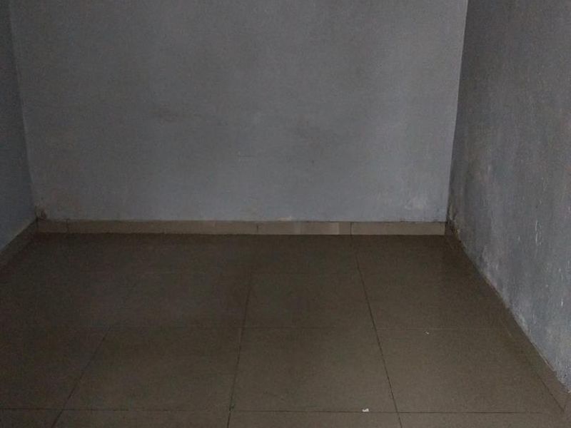 An empty, unfurnished room featuring tiled flooring and plain walls, requiring cosmetic updates to improve its overall condition and appeal.