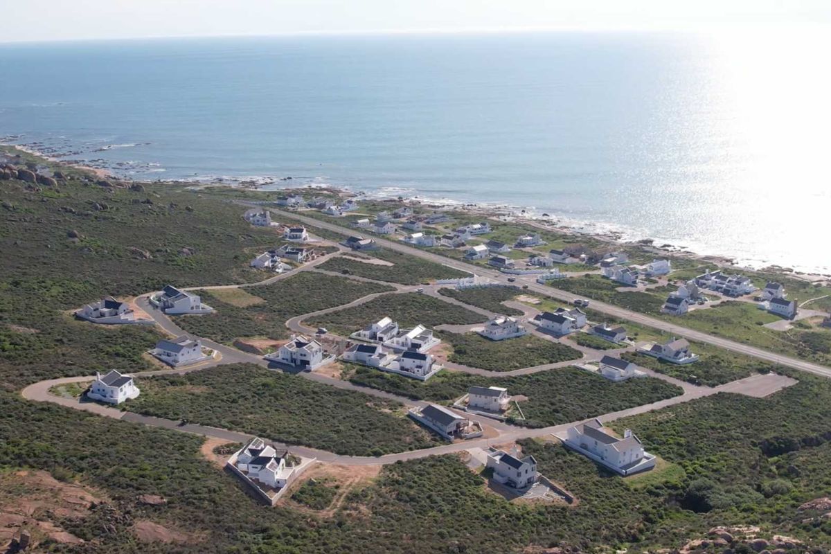 Aerial view of a coastal residential estate featuring detached homes situated near the ocean with established road infrastructure.