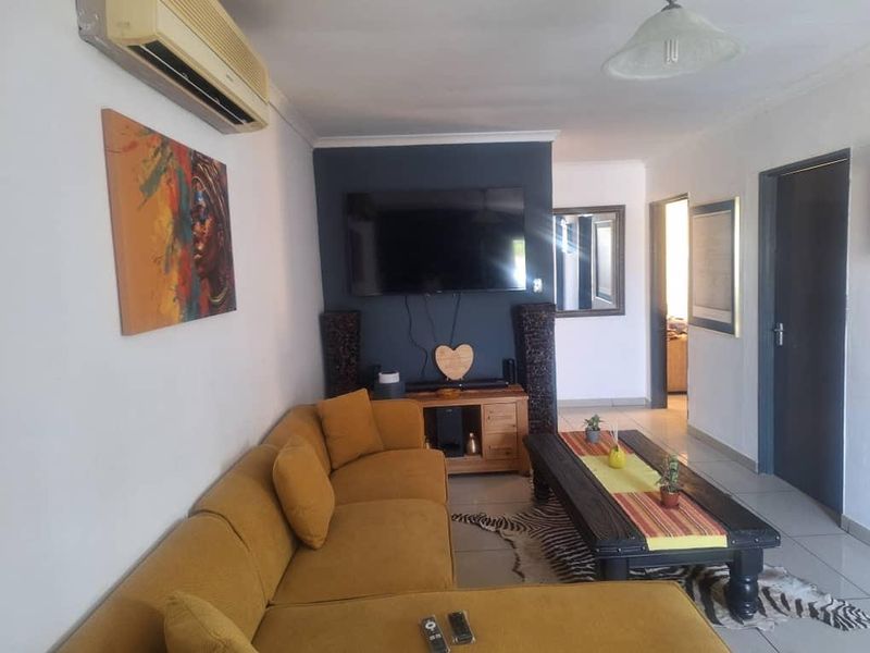A comfortable living room featuring tiled flooring, a wall-mounted air conditioning unit, and a dark accent wall.