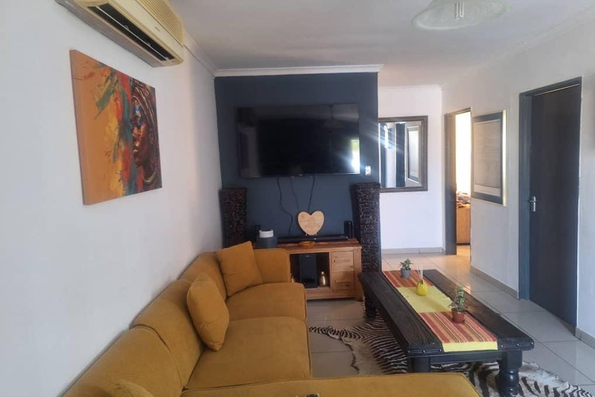 A comfortable living room featuring tiled flooring, a wall-mounted air conditioning unit, and a dark accent wall.