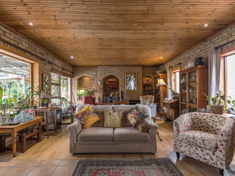 Spacious living room featuring exposed brick walls, a warm timber-clad ceiling, and large windows that provide ample natural light.