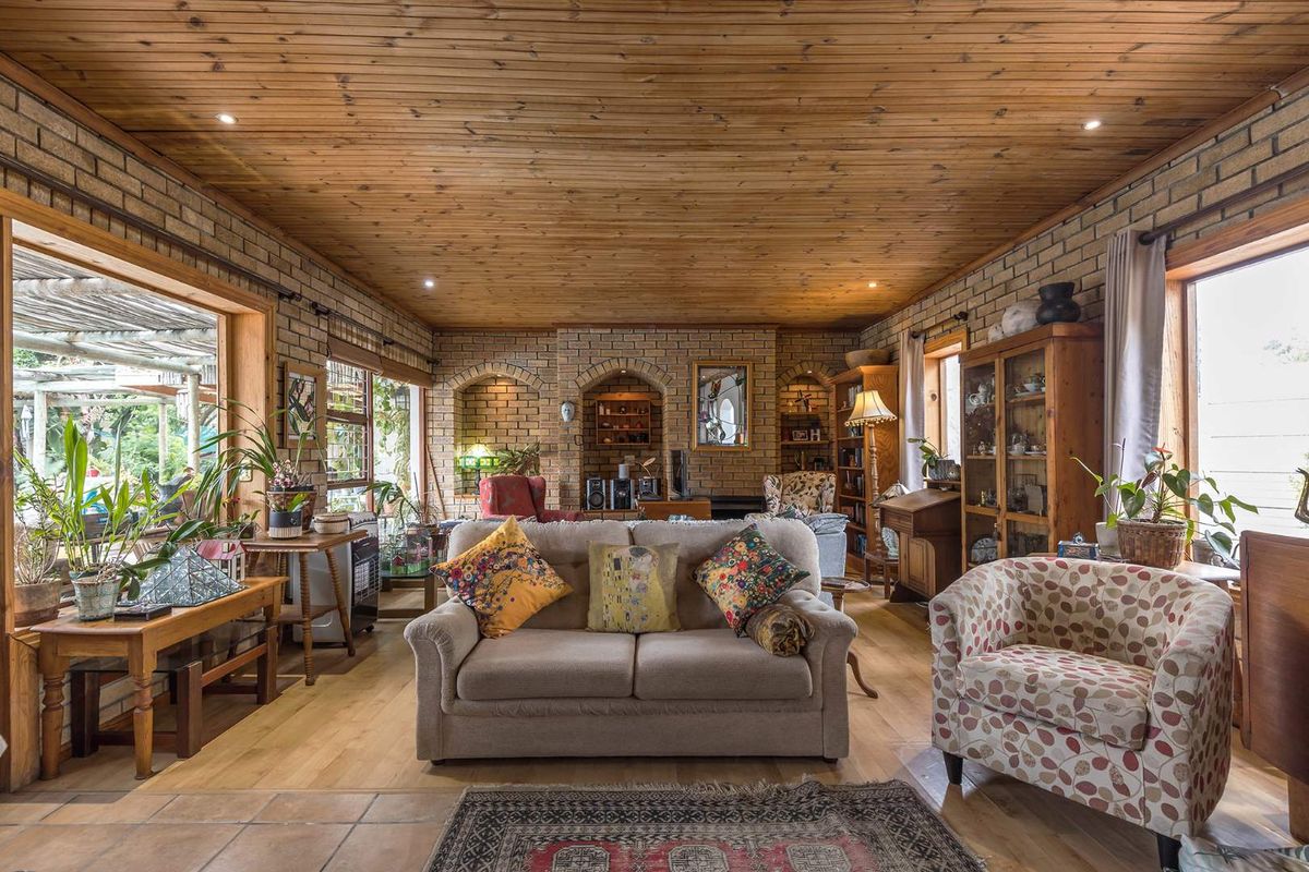 Spacious living room featuring exposed brick walls, a warm timber-clad ceiling, and large windows that provide ample natural light.
