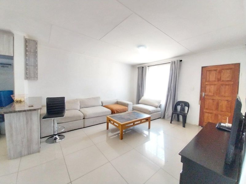 Open plan living area featuring tiled flooring, a breakfast bar, and a solid timber entrance door.