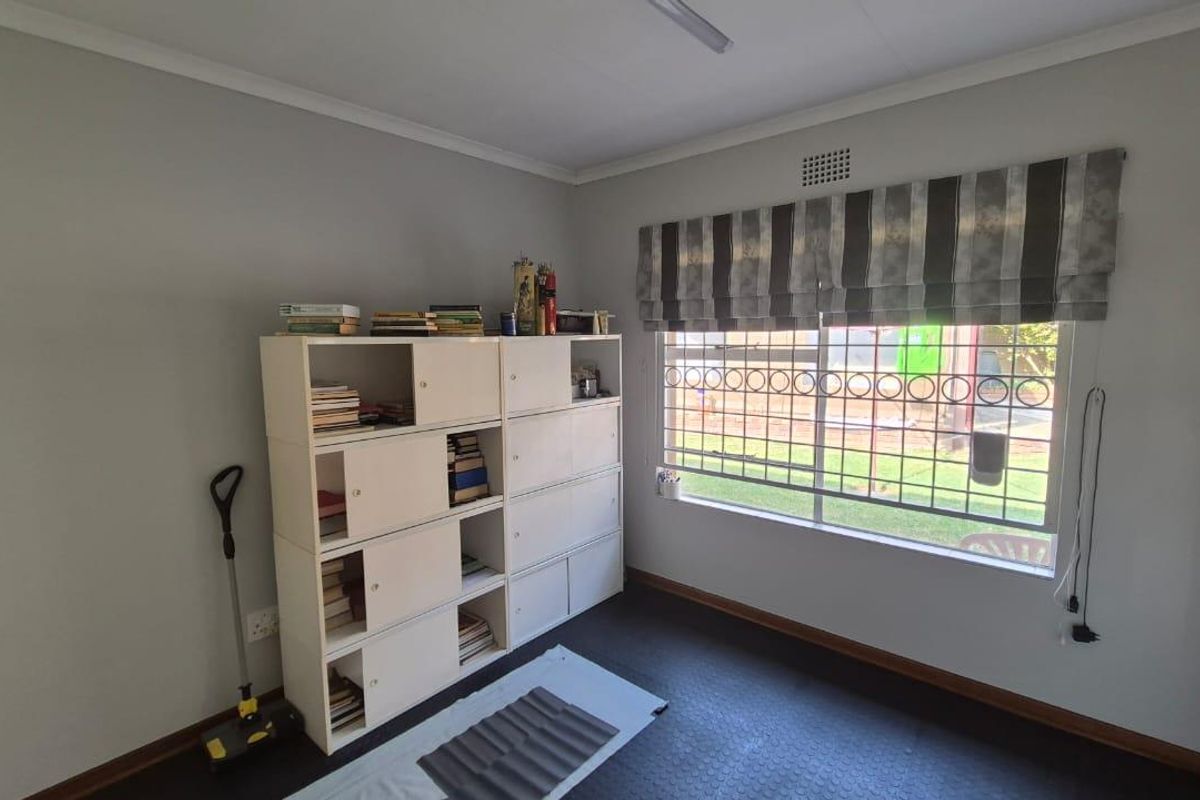 A bedroom featuring vinyl flooring, security bars on the window, and neutral wall finishes, offering a functional space ready for personalization.