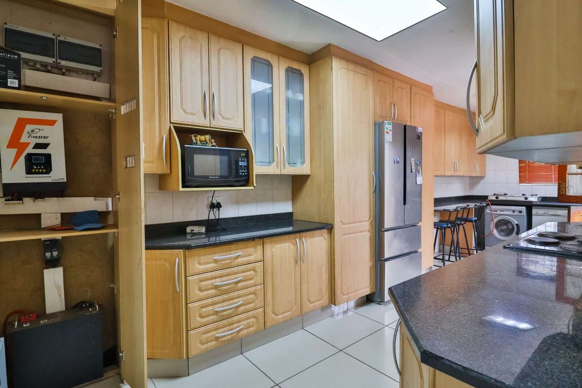 A functional kitchen featuring light wood cabinetry, granite countertops, tiled floors, and integrated laundry facilities, offering a practical layout for daily use.