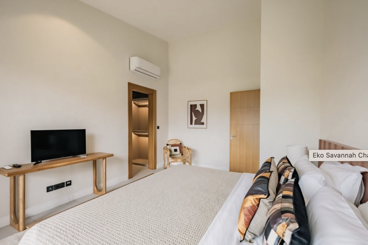 A well-maintained bedroom featuring neutral tones, a walk-in closet, and a wall-mounted air conditioning unit.