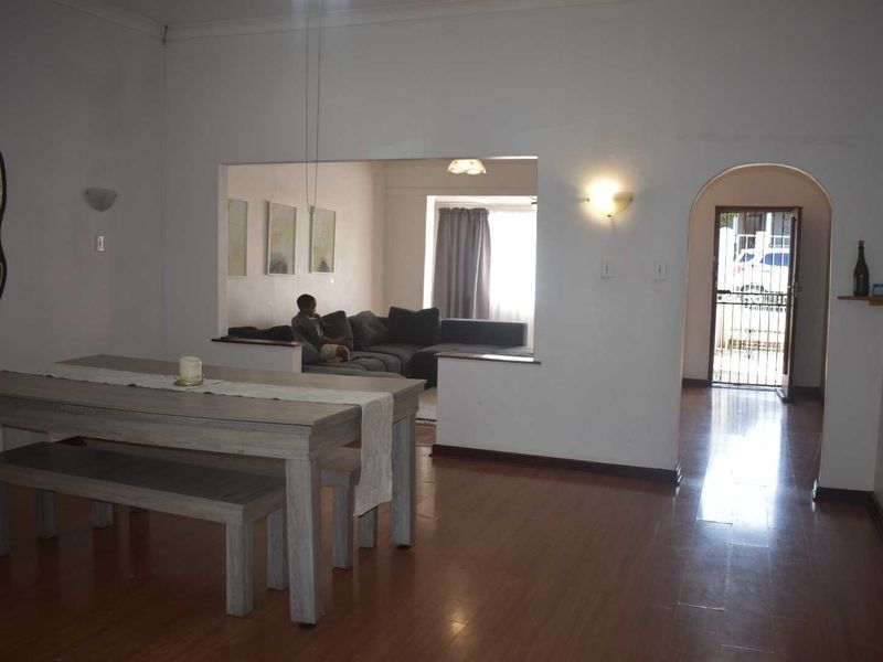 Open plan living and dining area featuring laminate flooring, arched entryway, and wall-mounted lighting fixtures.
