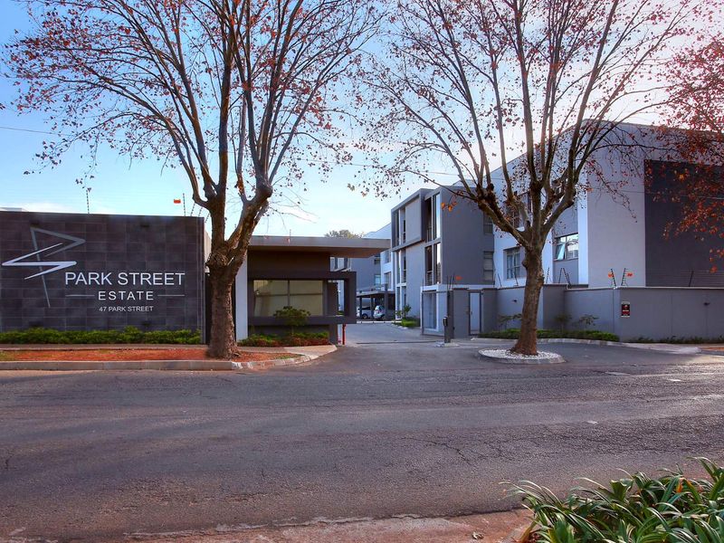 Street view of the Park Street Estate entrance, featuring a modern security gatehouse, paved driveway, and perimeter wall with electric fencing.