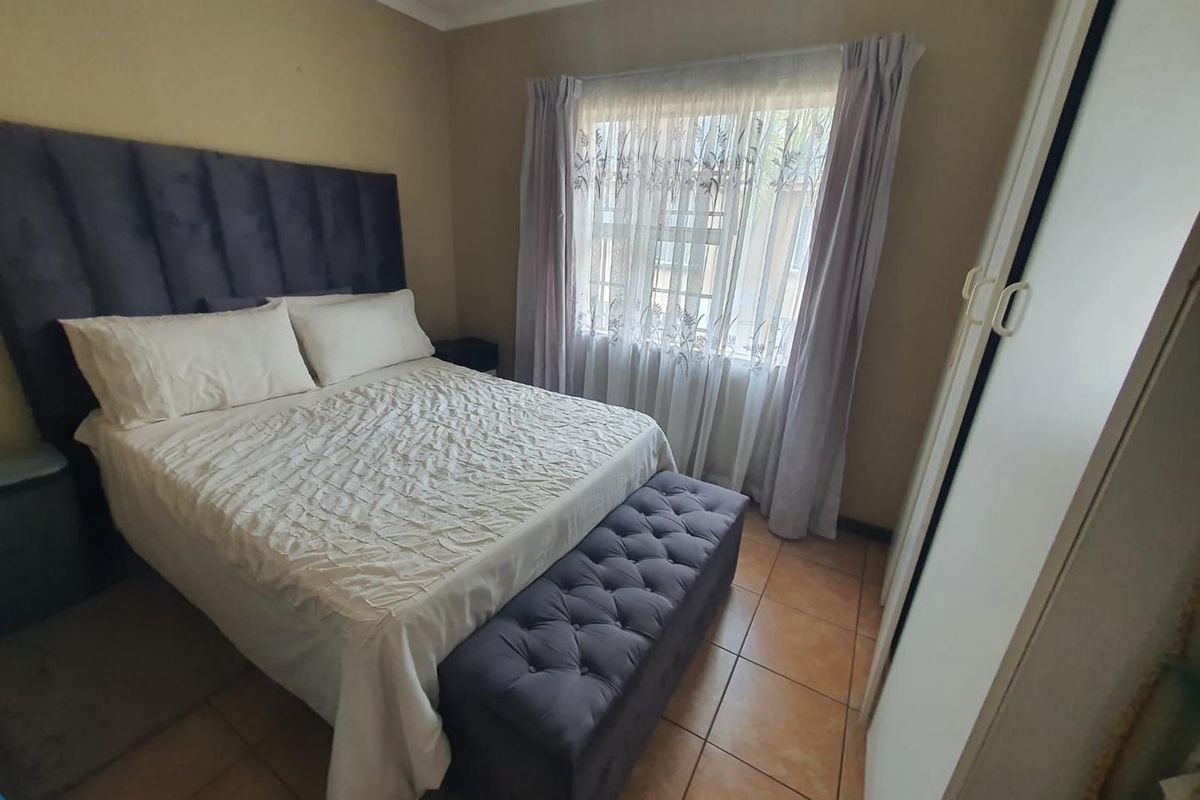 A bedroom featuring tiled flooring and a built-in wardrobe, offering a functional space with natural light from the window.