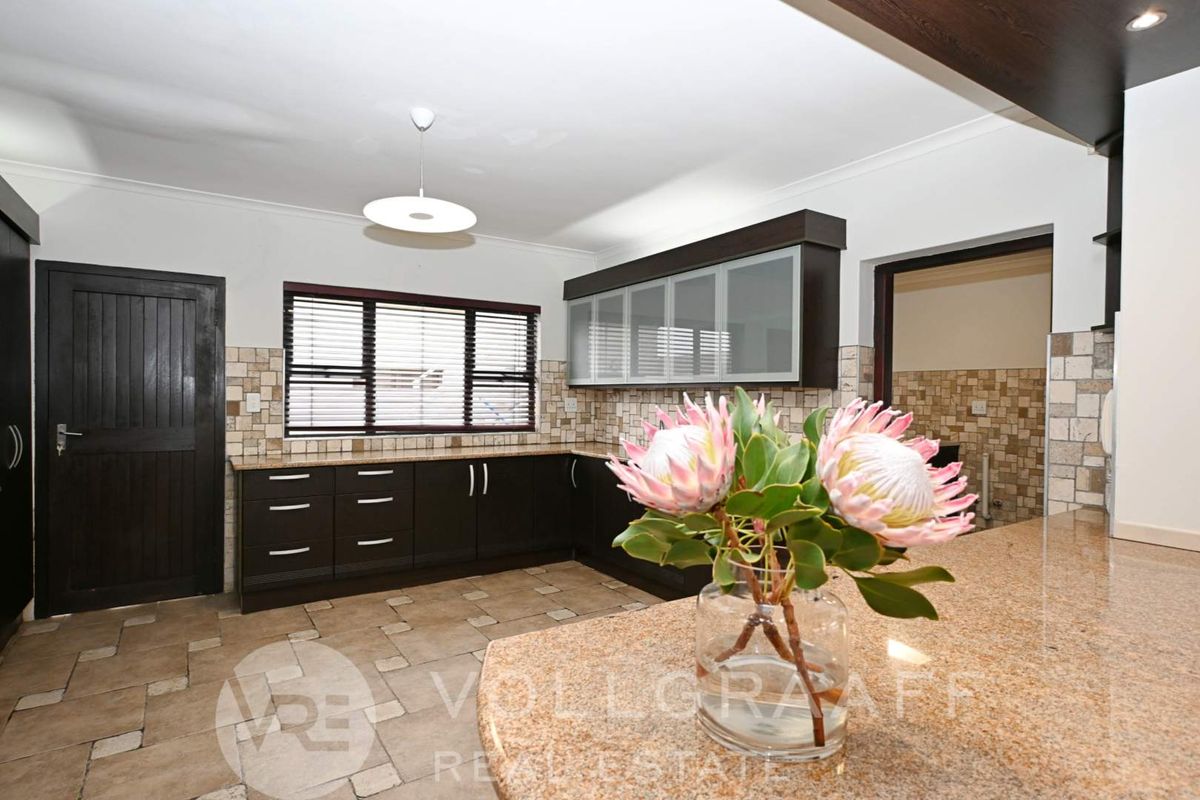 A well-maintained kitchen featuring dark cabinetry, granite countertops, tiled backsplash, and tiled flooring with a functional layout.