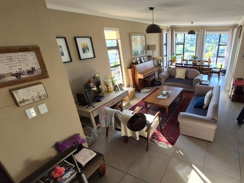 Spacious open-plan living and dining area featuring large windows, tiled flooring, and natural light, creating a comfortable and inviting atmosphere.