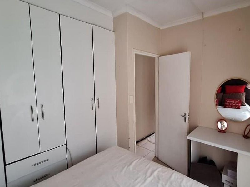 A bedroom featuring white built-in cupboards and a matching built-in vanity unit with a circular mirror.
