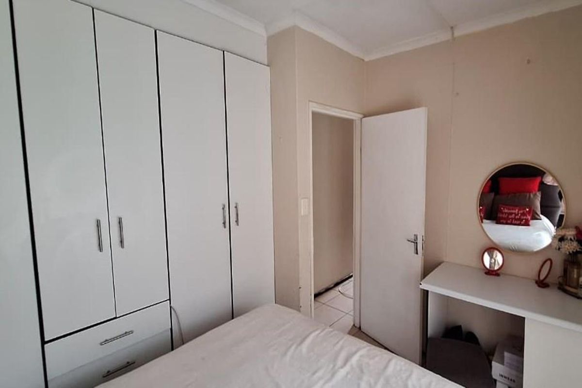 A bedroom featuring white built-in cupboards and a matching built-in vanity unit with a circular mirror.