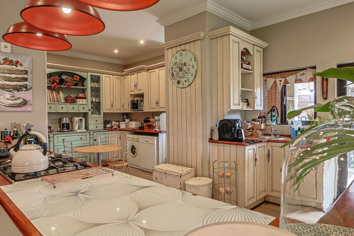 A charming country-style kitchen featuring cream cabinetry, wooden countertops, a built-in gas hob, and a dedicated scullery area with integrated laundry appliances.