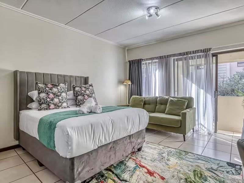 A well-lit bedroom featuring tiled flooring and a sliding glass door providing access to an outdoor balcony area.