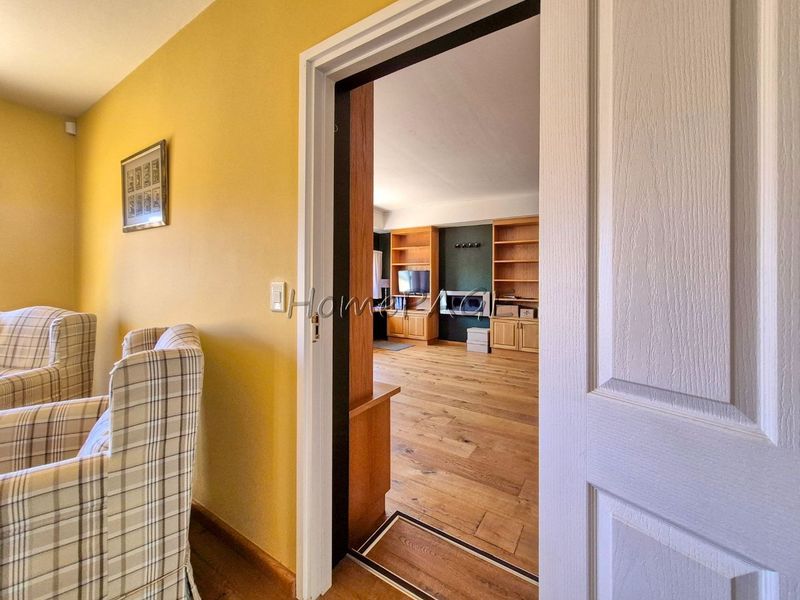 View through a doorway into a living area featuring hardwood flooring, built-in wooden shelving, and a fireplace.