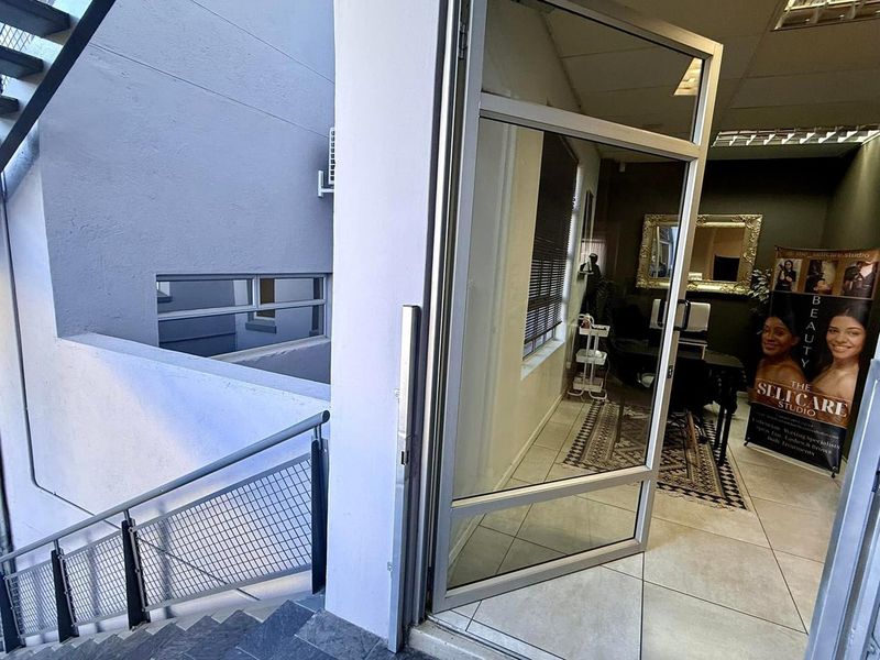 Entrance area featuring a glass door leading into a tiled office space with an adjacent external staircase.
