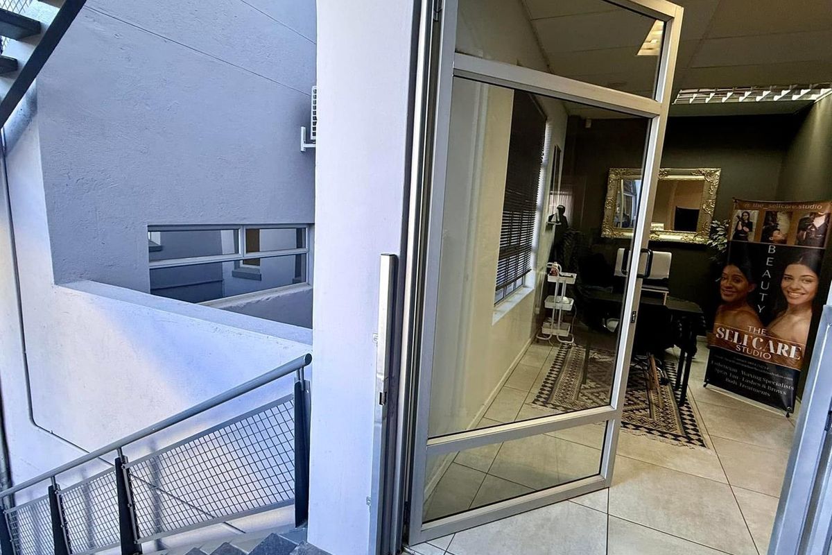 Entrance area featuring a glass door leading into a tiled office space with an adjacent external staircase.