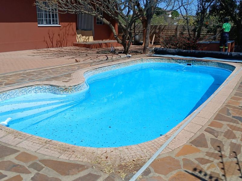 Outdoor swimming pool area featuring a paved patio surround and boundary wall, providing a private space for recreation and relaxation.