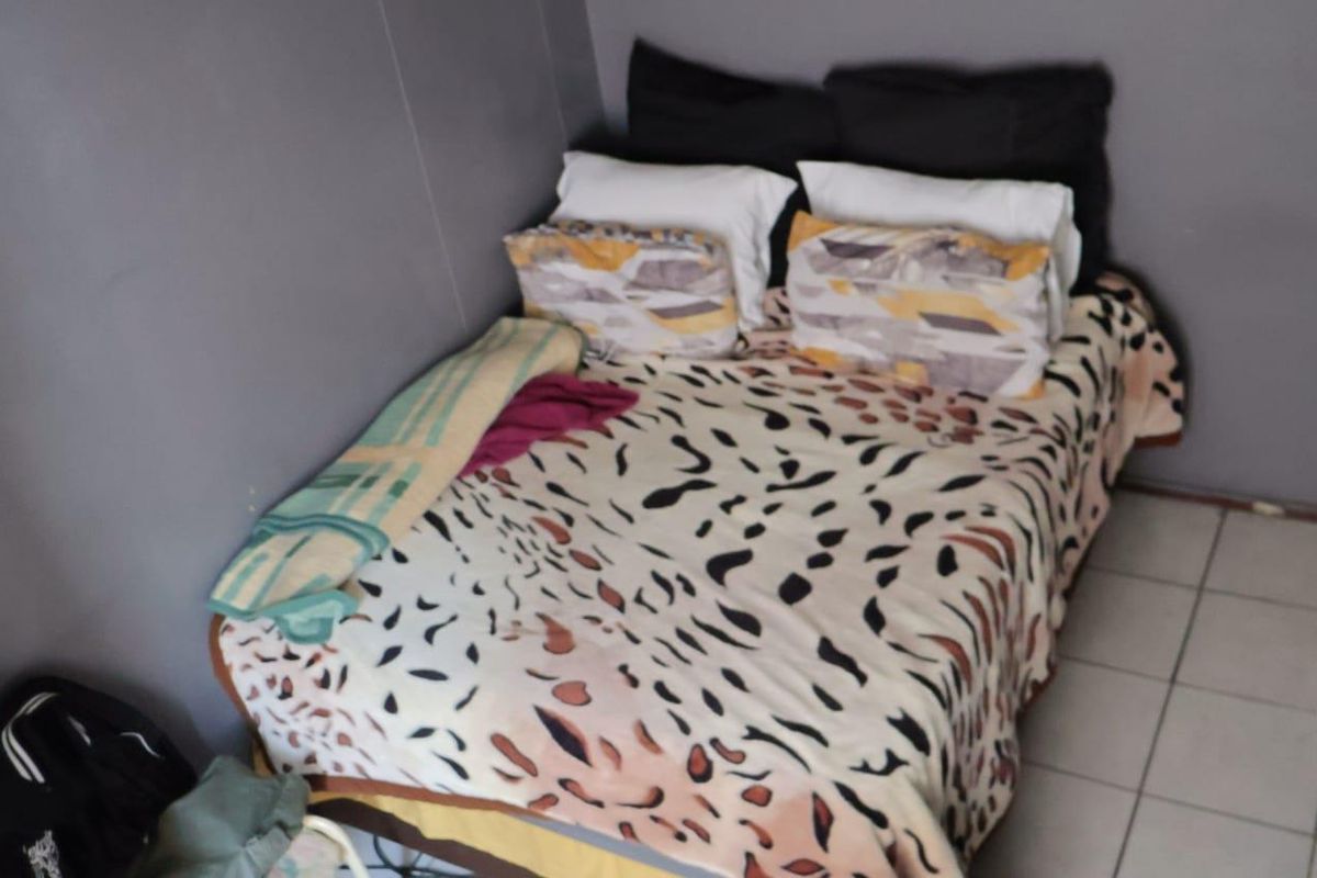 A compact bedroom featuring tiled flooring and grey painted walls.