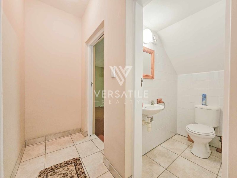 A compact guest bathroom featuring a wall-mounted basin and toilet with tiled flooring and wall finishes.
