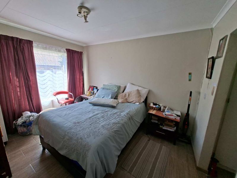 A standard bedroom featuring tiled flooring, coved ceilings, and a large window allowing natural light into the space.