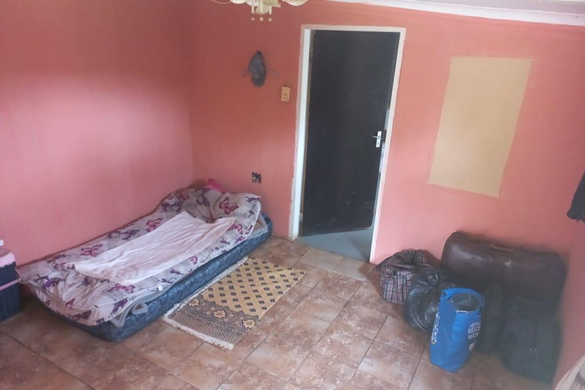 A bedroom featuring tiled flooring and a ceiling light fixture, currently requiring cosmetic updates and wall repairs.