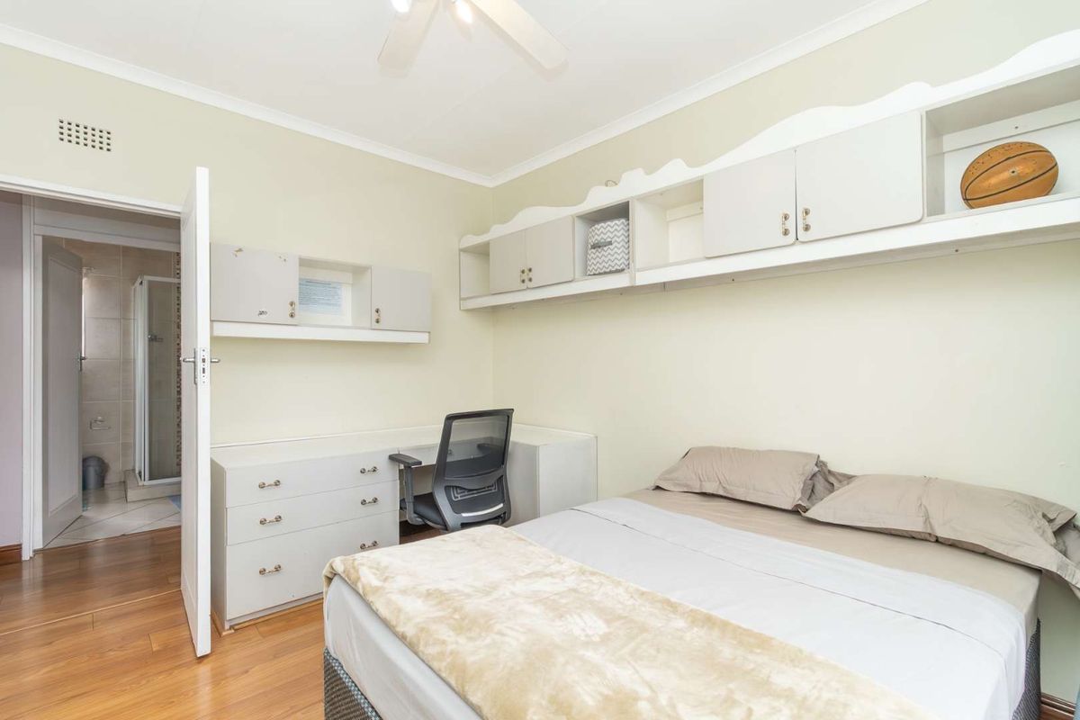 Bedroom featuring built-in cabinetry, a desk area, ceiling fan, and laminate flooring, with direct access to an en-suite bathroom.