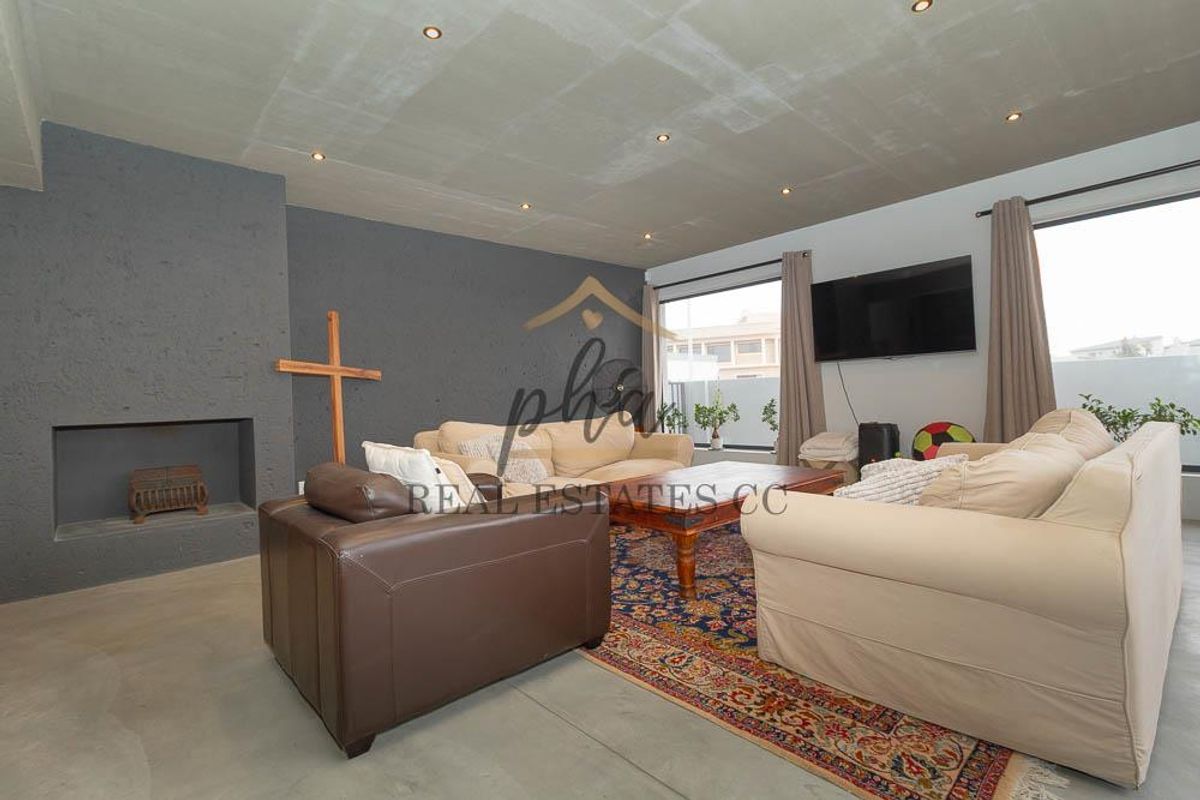 Spacious living room featuring a modern concrete ceiling, recessed lighting, and a large built-in fireplace with a textured grey feature wall.
