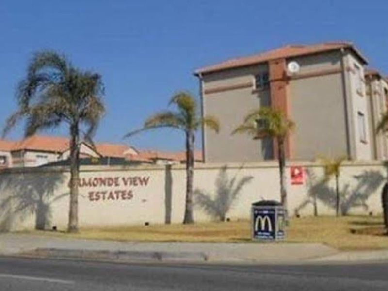 Exterior view of the Ormonde View Estates apartment complex, featuring perimeter walling, landscaped palm trees, and multi-story residential building blocks.