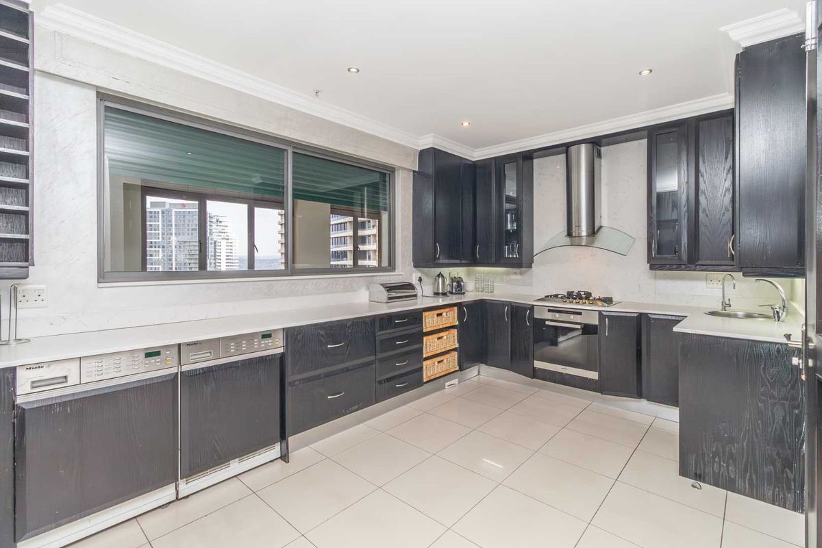 Modern kitchen featuring dark wood cabinetry, stone countertops, integrated appliances, gas hob, and large windows with city views.