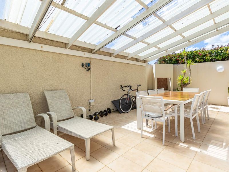 A covered outdoor patio area featuring tiled flooring and a translucent roof, providing a versatile space for dining and relaxation.