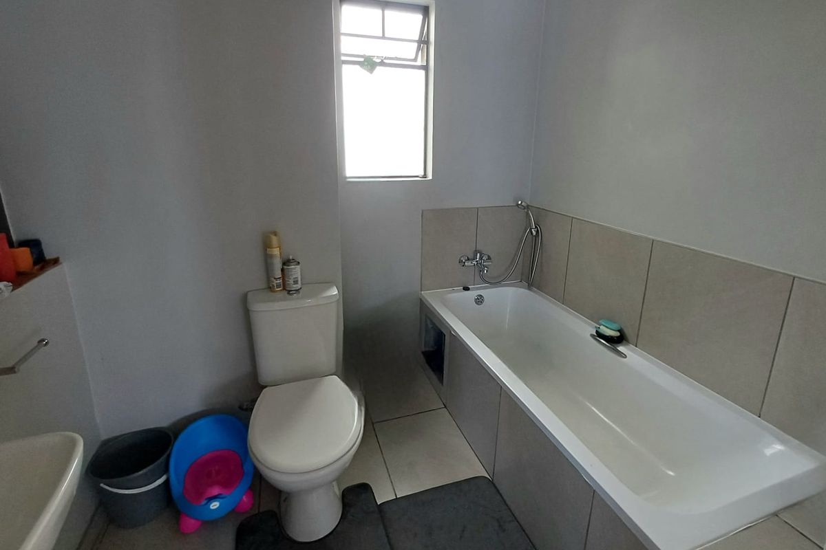 A functional bathroom featuring a standard bathtub with shower mixer, a toilet, and tiled wall surrounds.