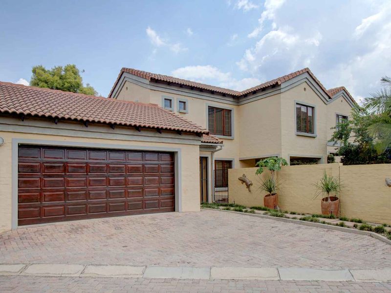 Front elevation of a double-story townhouse featuring a paved driveway, a double timber garage door, and a classic terracotta tiled roof.