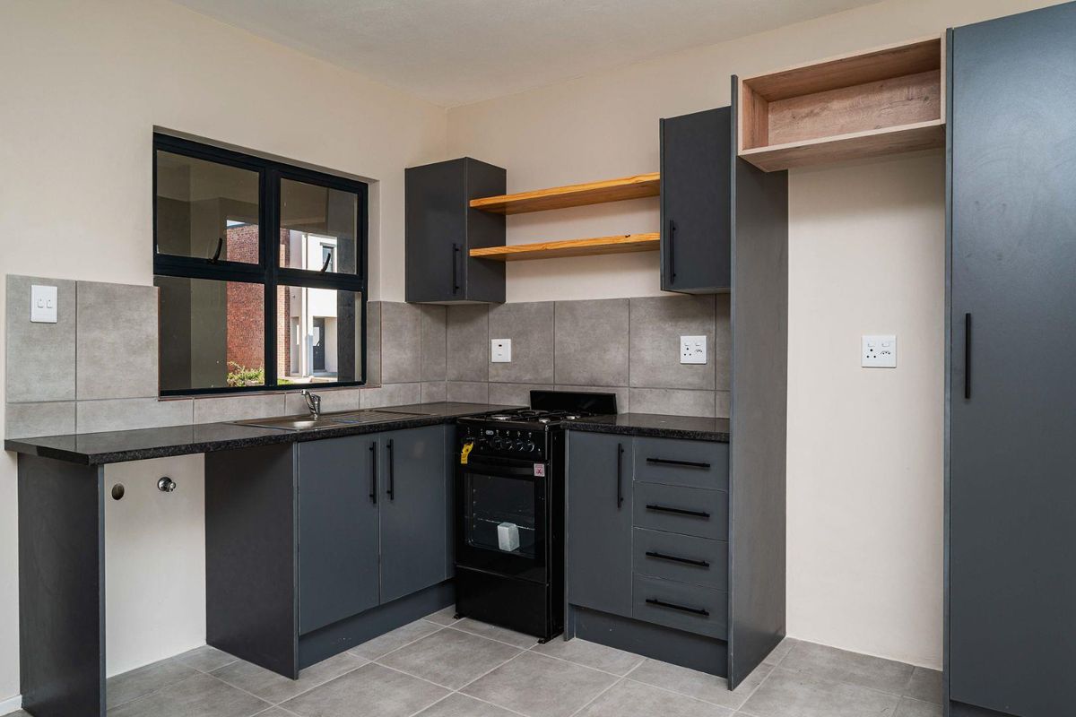 Modern kitchen featuring dark grey cabinetry, granite countertops, tiled backsplash, and a freestanding stove, offering a clean and functional workspace.