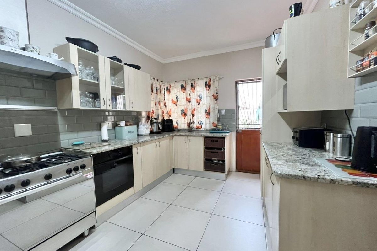 A functional kitchen featuring light-toned cabinetry, granite countertops, tiled backsplash, and a built-in oven with a gas hob.